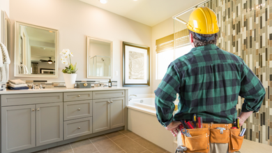  Bathroom remodel contractor inspecting modern bathroom renovation with upgraded cabinetry and tile.