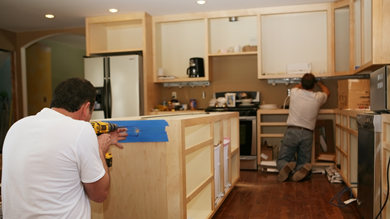 Kitchen remodel with contractors installing cabinets and working on a new kitchen island.